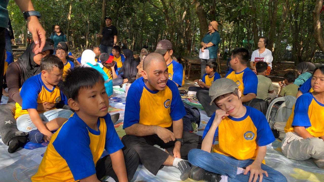 Siswa dan guru duduk bersama saat piknik di taman