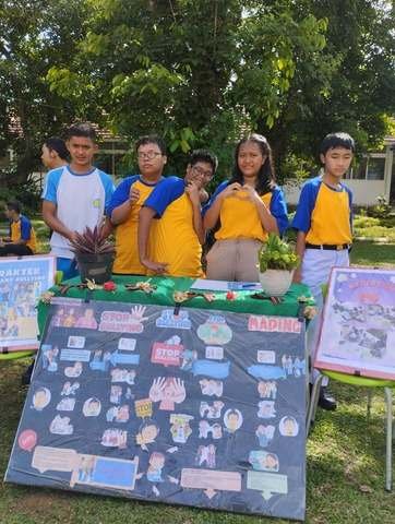 Siswa berpose di samping mading karya bertema stop bullying