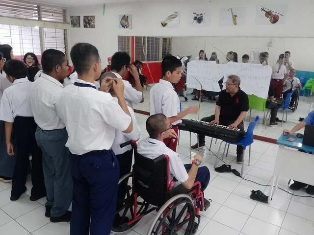 Kelas seni musik dengan siswa berdiri mengelilingi guru