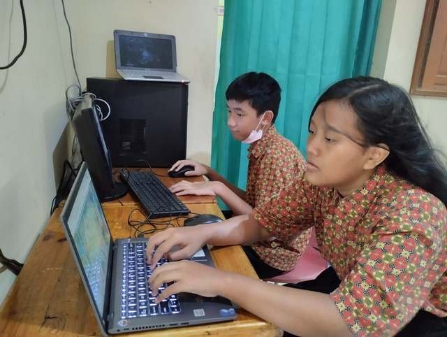 Dua siswa mengetik di laptop